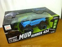 Boxed 1:14 scale Gravity Mud Runner 4x4 truck with visible clear window showing the blue and black truck inside.