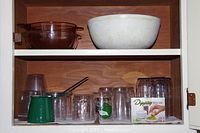 Top shelf with large amber glass bowl and large white ceramic bowl on wooden shelf.