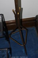 Wooden coat rack with dark finish and brass-tipped hooks on tripod base