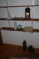 Shelf with assembled 3D models including Statue of Liberty, Leaning Tower of Pisa, small globe, Colosseum model, toy soldier figures, wood and metal sculptures.