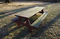 Photo of the wood picnic table and benches outdoors on grass with visible wear and weathering.