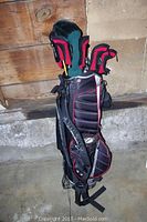 Full view of the golf bag showing black and red color with multiple clubs inside, bag straps visible.