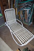 White reclining lawn chaise lounge chair with woven plastic straps and metal frame in used condition
