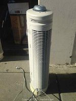 Full height view of Bionaire Arm & Hammer air purifier tower with visible power cord lying on ground.