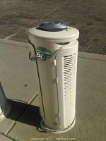 Front view of the tall beige Bionaire Arm and Hammer air purifier showing vent slats, control dial on top, and power cord