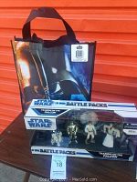 Photo showing unopened Star Wars Training on the Falcon Battle Pack with 4 action figures visible inside and Darth Vader themed bag behind it on a table.