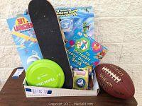 Overview of all items in the lot including football, skateboard, frisbee, yo-yo, bubble kit, and book