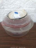 Stack of platters with metal leaf candy dish on top, showing different glass platter styles and pink depression glass platter.