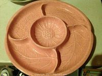 Close-up photo of one pink speckled ceramic flower platter with leaf and central flower design showing condition and detail