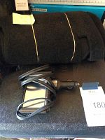 Rolled black Prius dashboard mat and rectangular black GPS car charger on textured surface