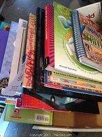 Stack of assorted puzzle and picture books viewed from the side, showing various colorful covers and bindings.