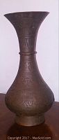 Full side view of the tall vintage brass vase showing detailed engraved Egyptian designs.