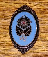Front view of the vintage Victorian enamel flower brooch showing blue enamel with hand-set stones and intricate metal frame.