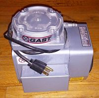 Side view of Gast compressor vacuum showing brand label, power cord, and overall metal construction.