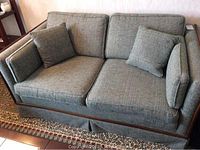 Front and side view of the loveseat sofa showing the wooden frame and fabric upholstery with matching cushions.