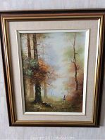 Framed painting of forest landscape with child in red hat.
