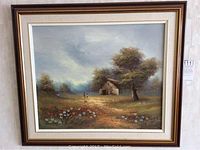 Framed landscape painting showing a countryside scene with barn, trees, wildflowers, and figure walking.