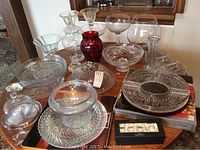 Top view of table holding multiple glass and crystal items showing variety of dishes, bowls, vases, and candle holders.