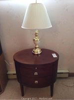 Side table with brass lamp on top against wall with baseboard heater