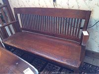 Front left angled view showing slatted back, armrest, and seat wear
