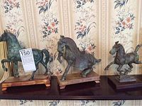 Three verdigris metal horse sculptures on wood bases