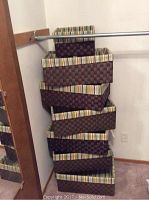 Stacked view of six large and three smaller woven baskets with striped lining against a wall.