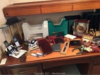 Wide view of entire desk showing organizers, phones, clock, leather items, and other desk accessories