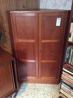 Closed corner cabinet showing dark wood finish and panelled doors with horizontal trim detail.