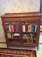 Front view of stained oak veneer bookcase with two glass doors filled with books
