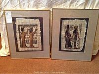 Pair of framed Egyptian paintings on linen fabric with gold-tone frames and neutral mats