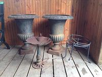 Pair of cast iron urns, bird bath and two plant pot holders on wooden floor