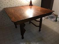 View of antique oak kitchen table showing wood grain and turnings on legs clearly.