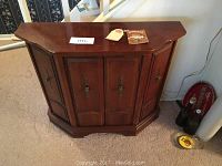Front view of cherry wood Monitor Furniture entry chest with three paneled doors and brass hardware handles.