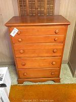 Front view of a pine four drawer dresser with round wooden knobs and smooth wood finish.