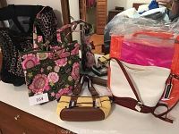 Lot of handbags on a dresser showing a black leopard print bag, a floral Vera Bradley bag, white crossbody bag, and a yellow Giani Bernini handbag with tag