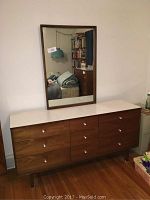 Front view of the 9-drawer Bassett Furniture dresser with attached mirror and white formica top, showing wood grain finish and metal hardware knobs.