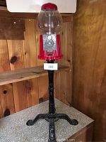 Front angle view of the 1985 Carousel gum ball machine sitting on the black metal stand with four-legged base, showing the globe and coin mechanism.