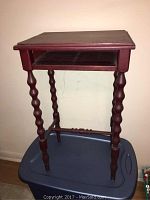 Side view of vintage wooden stand showing turned legs and open shelf.