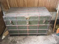 Closed view of the vintage green travel steamer trunk showing metal reinforcements, latches, and lock clasp on the front.