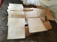 Several metal printing plates laid out in an open box, showing their embossed reverse text and images for newspaper printing.