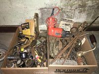 Overview of assorted hand tools, taps, dies, hole saws, and a Black & Decker orange drill among other tools in a box.