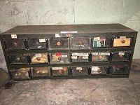 Front view of metal storage cabinet with 24 small drawers, each labeled and having wooden knobs.