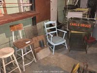 Wide shot showing two stools, blue armchair, plexiglass panels stacked, and Carls Drugs box