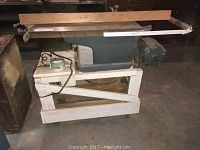 Left side view of Craftsman table saw on wooden stand with cast iron top and wooden rails.