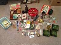 Full overview of the lot showing ashtrays, bottle openers, swizzle sticks, trinket boxes, coasters, and brewery collectibles arranged on a carpet.