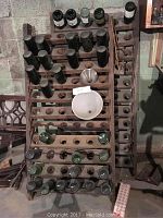 Top view of two wooden wine racks holding multiple empty wine bottles and two metal funnels