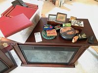 Electric fireplace heater with dark wood casing and assorted vintage collectibles on top, including books and tins
