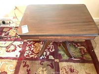 Top view of square wooden end table with polished surface showing wood grain, placed on floral patterned rug
