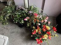 Overall photo showing multiple faux flower and greenery arrangements next to a mirrored wardrobe on a beige carpet.