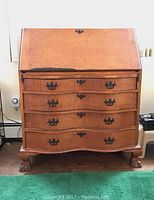 Front view of secretary desk showing four drawers and folded drop front with claw feet and oil rubbed bronze hardware.
